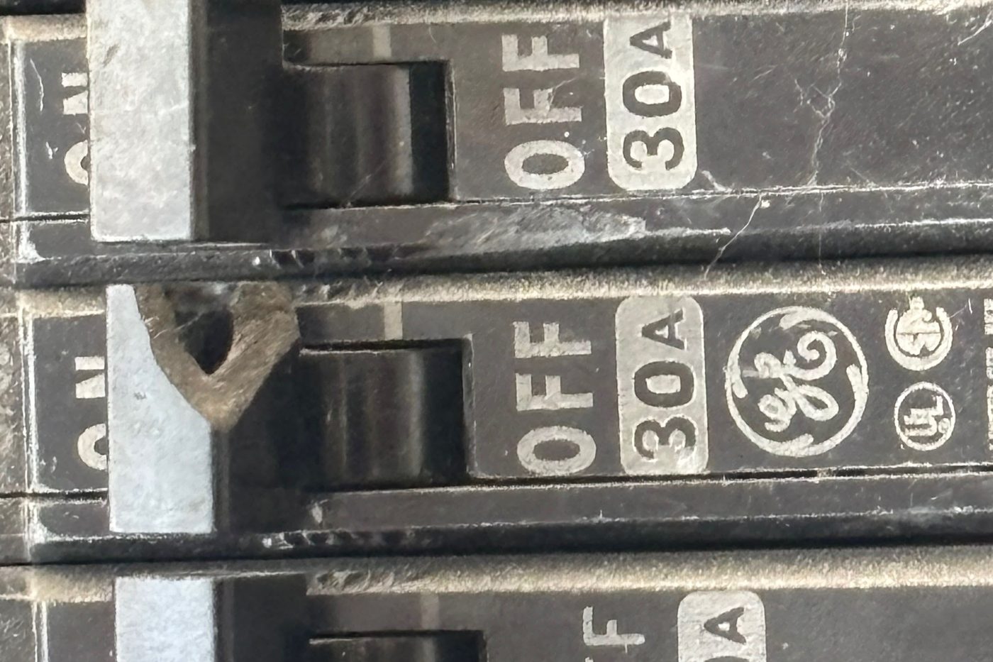 Two 30-amp breakers side by side with the metal handle tie between them torn and broken