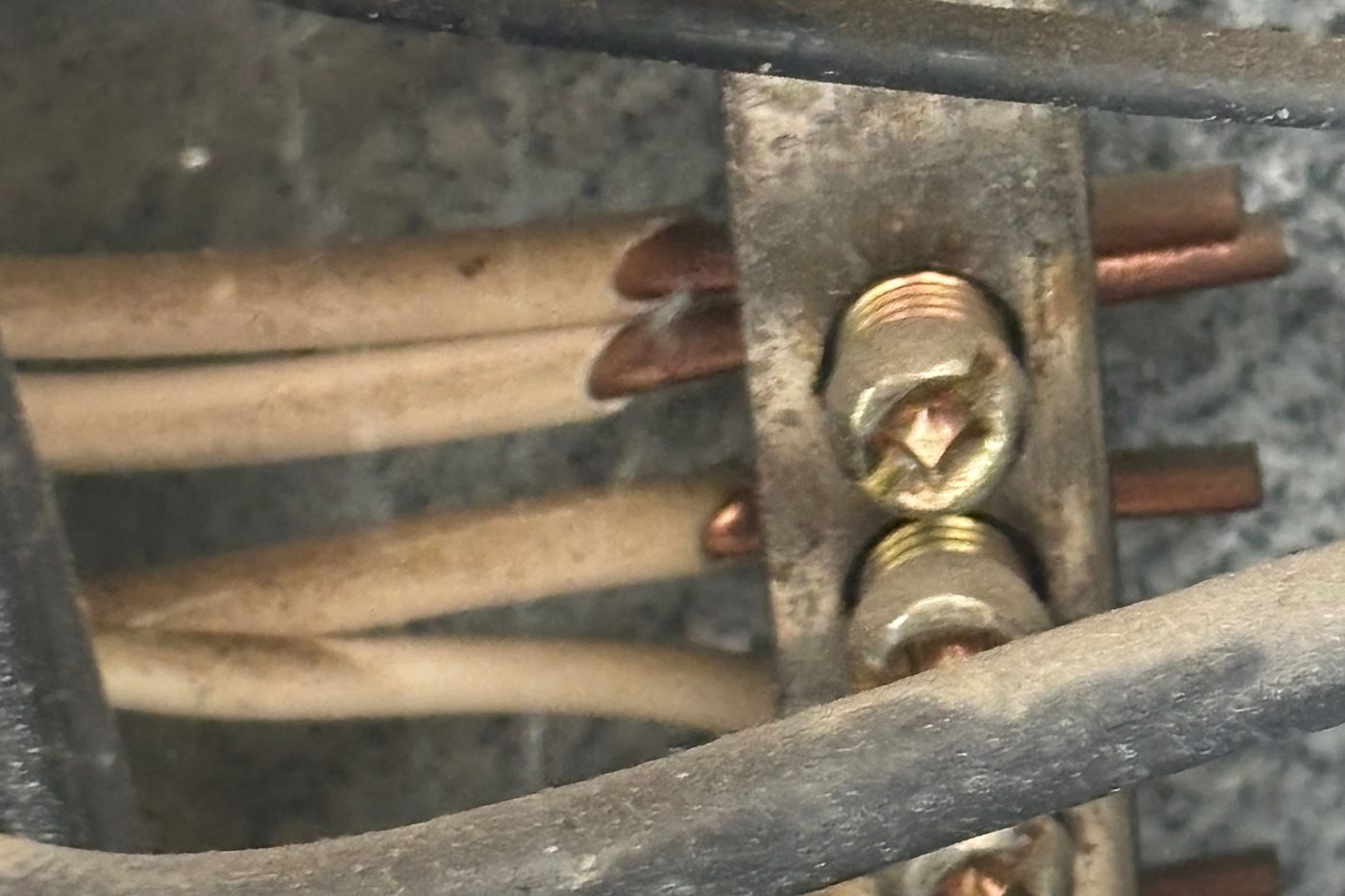 Neutral bar inside an electrical panel with white conductors landing under the terminal screws