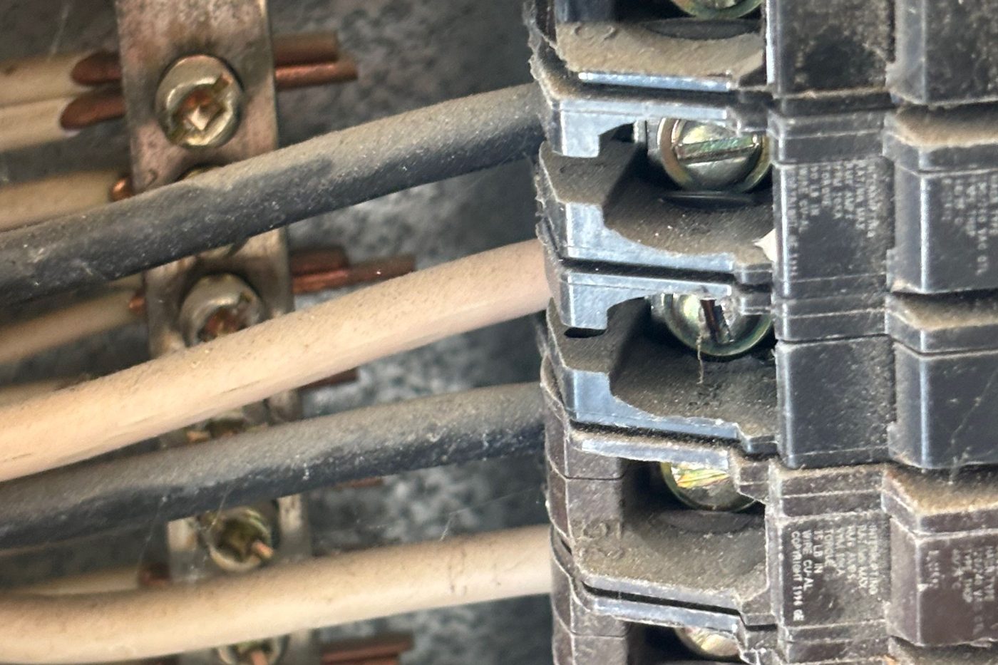 White-insulated conductors running to breaker terminals inside a residential panel, with no black or red tape marking them as energized