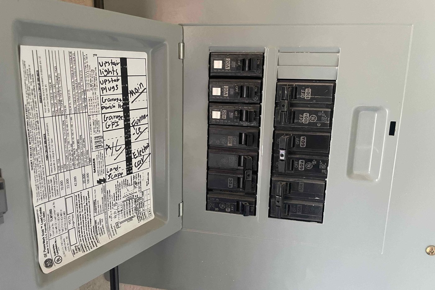 Breaker panel at the existing installation, cover open, breakers and wiring visible