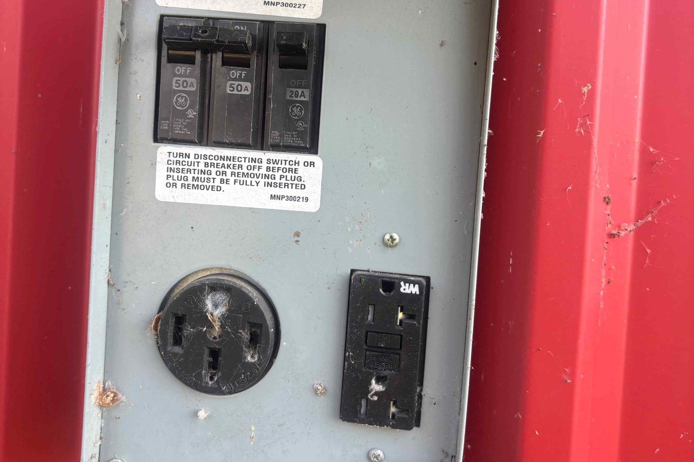 Existing RV power pedestal with a 50-amp receptacle and a 120-volt GFCI outlet, breakers visible inside