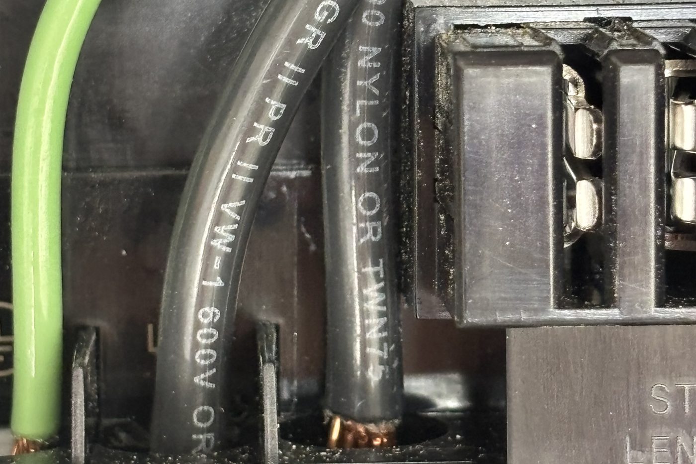 Black circuit conductors and a green ground wire entering the terminal block inside a Tesla Wall Connector