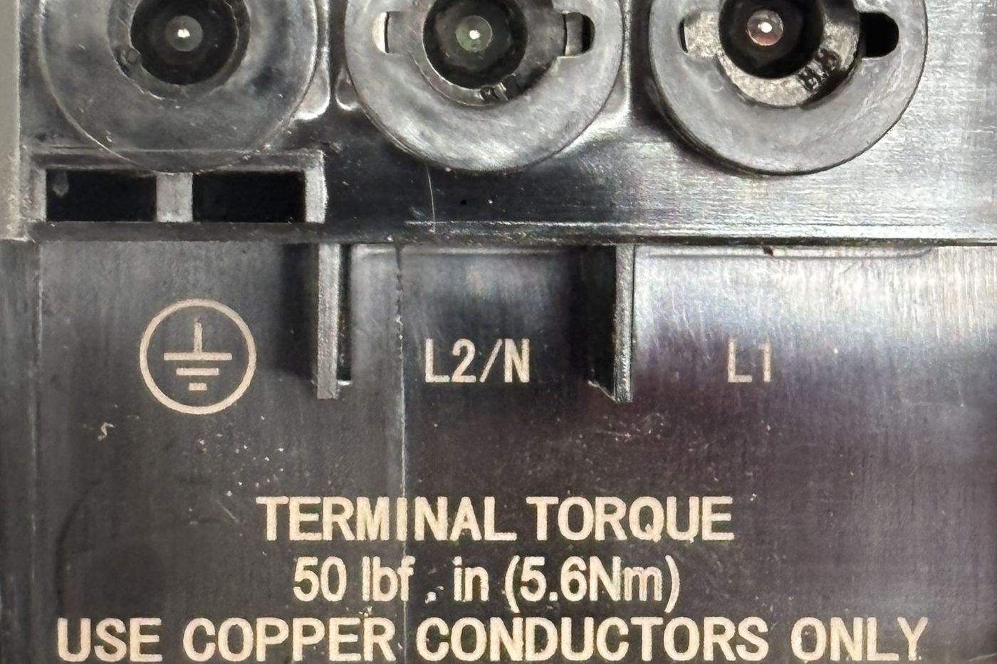 Wall Connector terminal block labelled ground, L2/N and L1, with the printed text: Terminal torque 50 lbf in (5.6 Nm), use copper conductors only